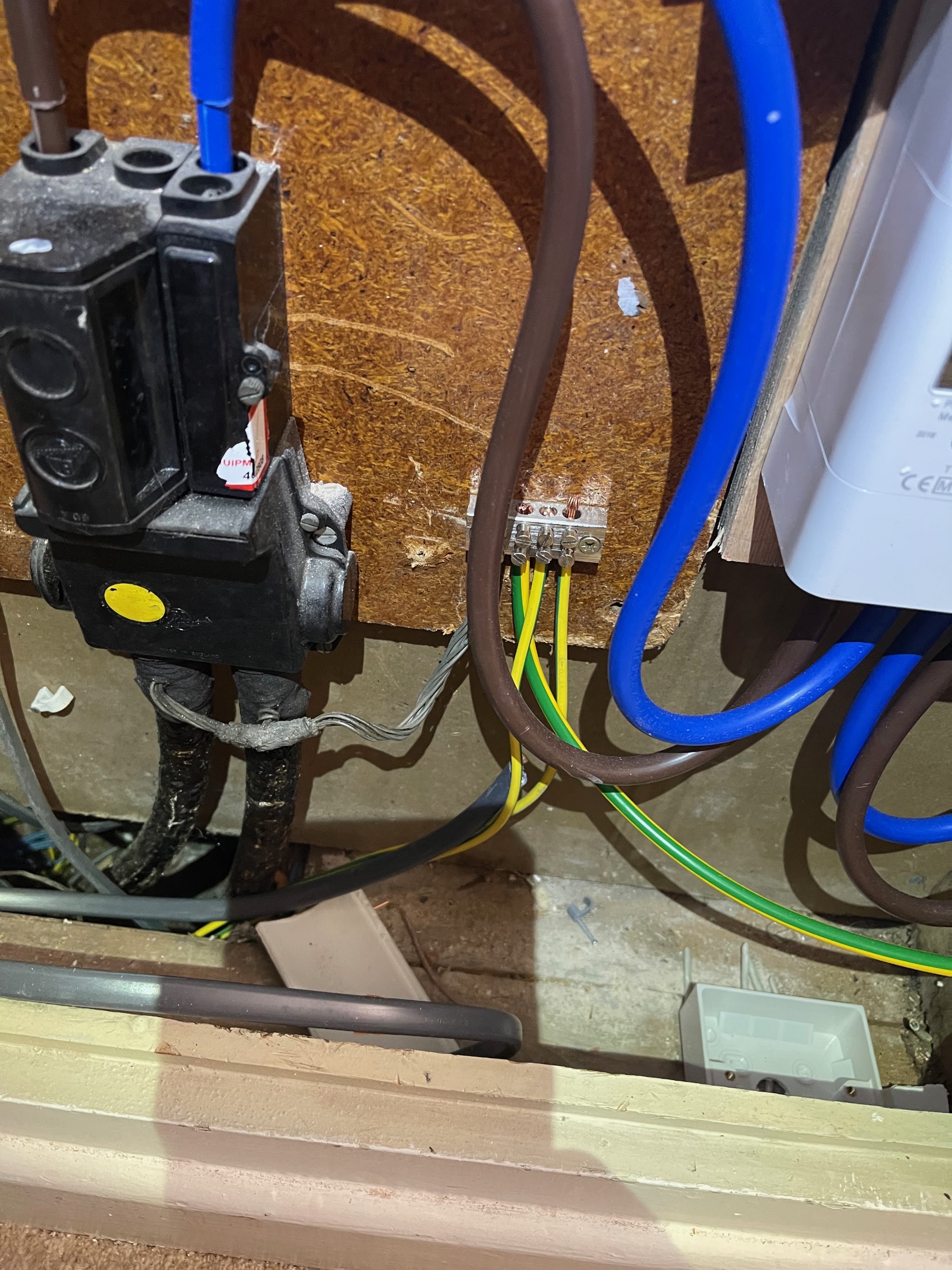 An earthing bar with green and yellow earth cables beside meter tails